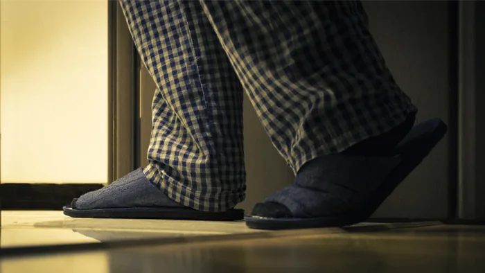 Un uomo in pigiama si alza dal letto di notte